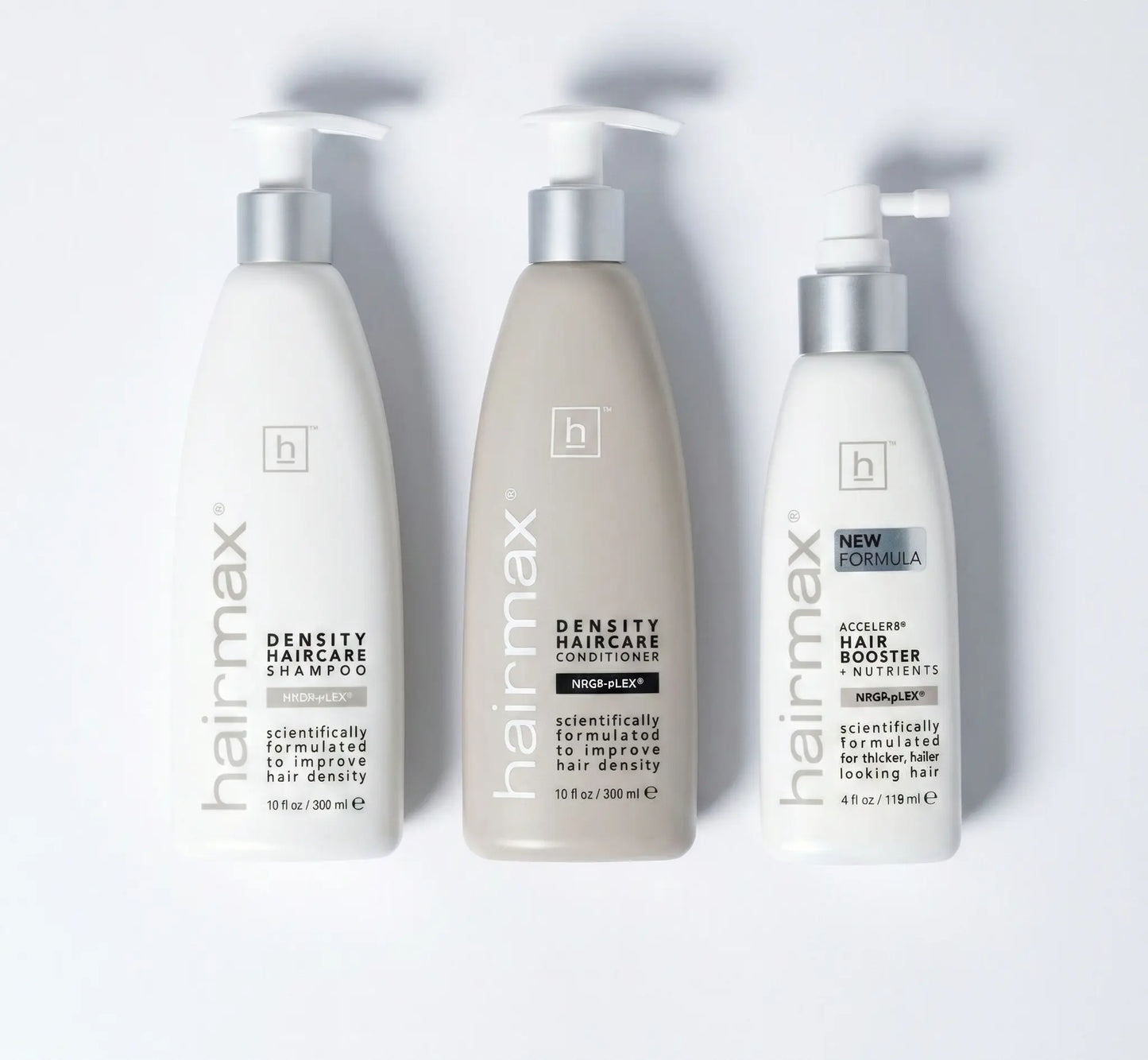 Three bottles of Hairmax hair care products on a white background