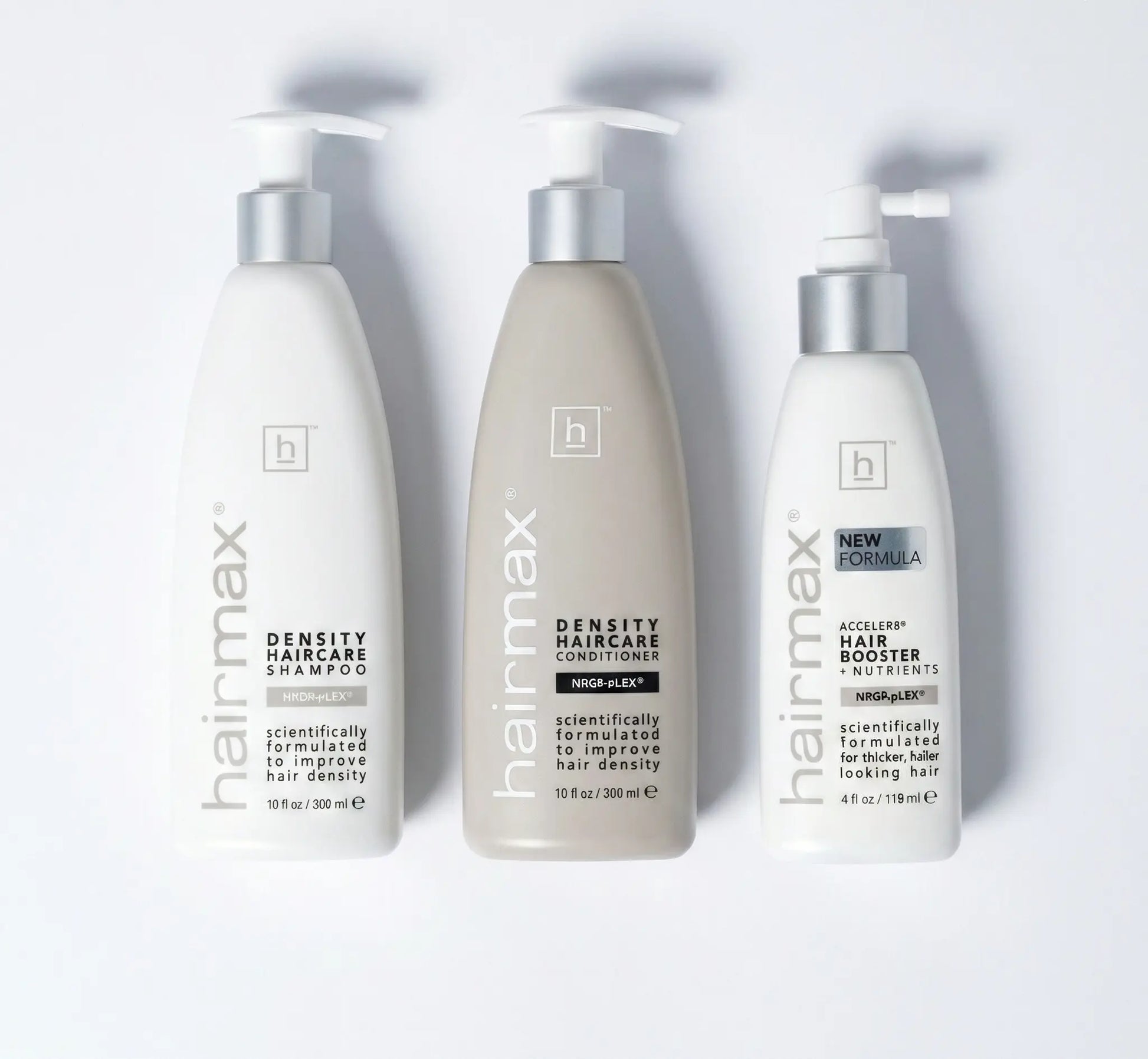 Three bottles of Hairmax hair care products on a white background